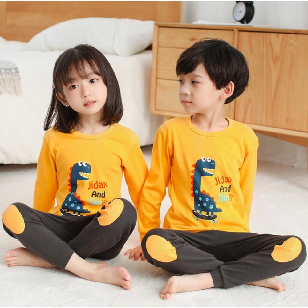 Kinderpyjama met gele dinosaurusustrui en bruine broek met twee kinderen die de pyjama dragen
