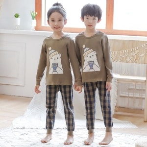 Lente pyjama met beige trui en geruite broek voor kinderen met twee kinderen het dragen van de pyjama is een achtergrond een kamer