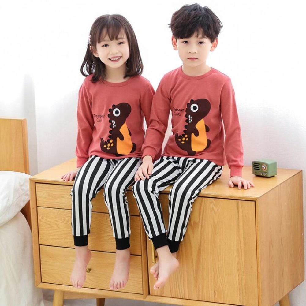 Lentepyjama met roze trui en zwart gestreepte witte broek voor kinderen met twee kinderen die de pyjama dragen en op het meubilair staan
