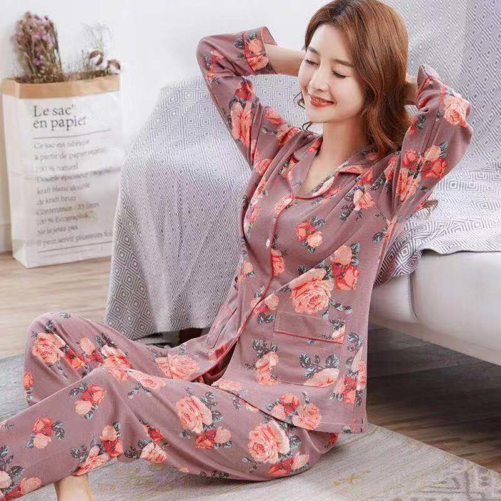 Tweedelige katoenen damespyjama met bloemmotief, gedragen door een vrouw zittend op een tapijt in een huis
