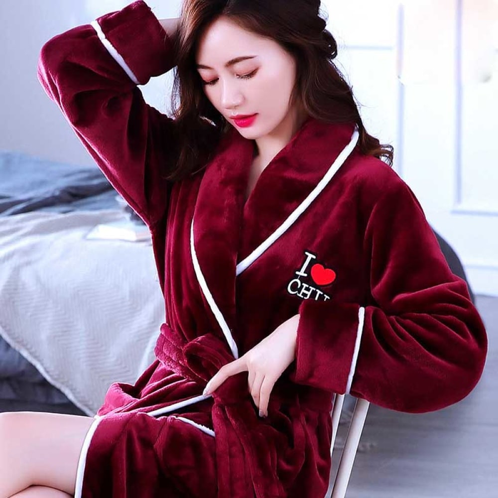Rode koraal fleece pyjama voor vrouwen van zeer hoge kwaliteit gedragen door een vrouw zittend op een stoel in een huis