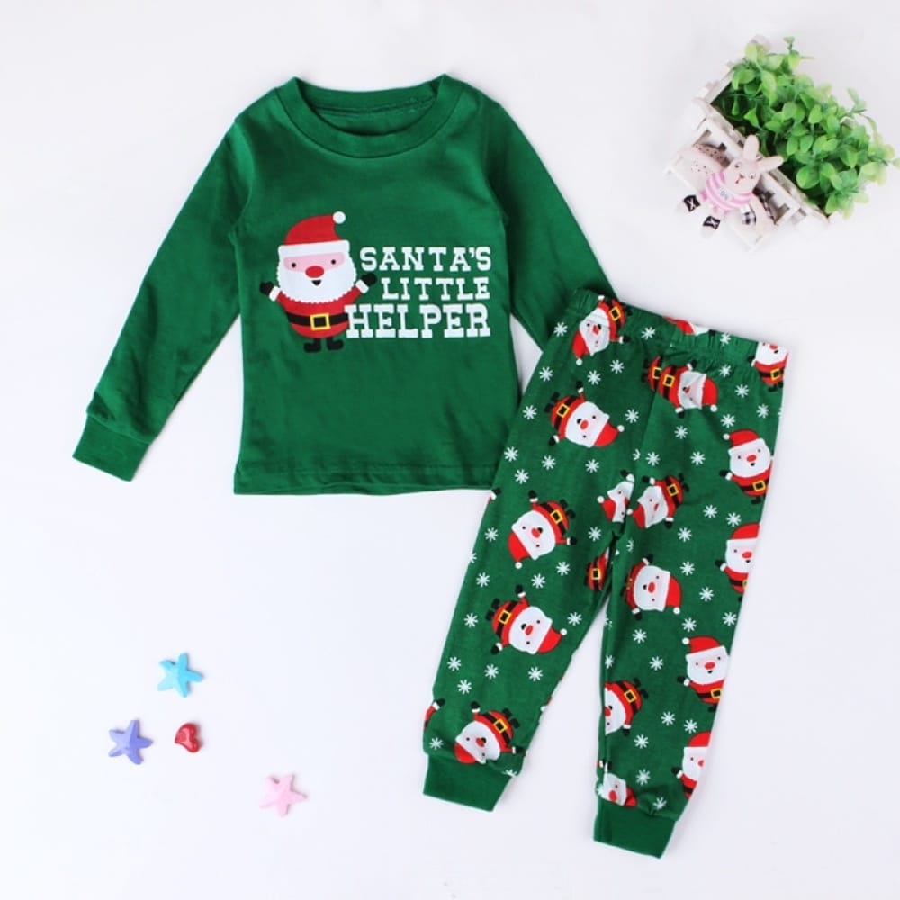 Santa's little helper" groene pyjama met witte achtergrond en een plant met sterren