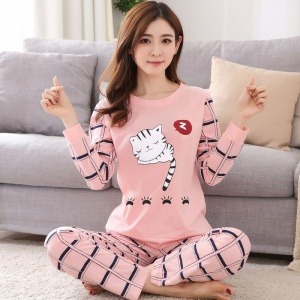 Schattige 2-delige pyjama met lange mouwen voor vrouwen gedragen door een vrouw zittend op een tapijt voor een stoel in een huis