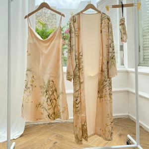 Sexy beige pyjama met bloemenprint hangend op hangers in een kamer met houten vloer en witte muur en voor een open raam
