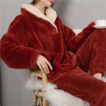 Rode fleece pyjama gedragen door een vrouw zittend op een houten stoel met een kopje thee in haar hand