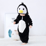 Baby in zwart pyjamapak in de vorm van een pinguïn kijkt naar zijn voeten